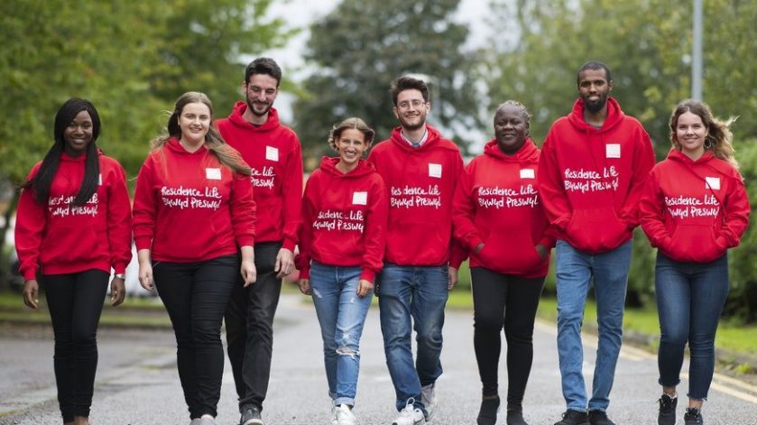 student accommodation support team at Cardiff walk in a line, with matching red hoodies on