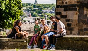 Five students sit outside together on a bright sunny day.