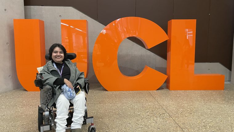 Kavya in front of a 'UCL' sign