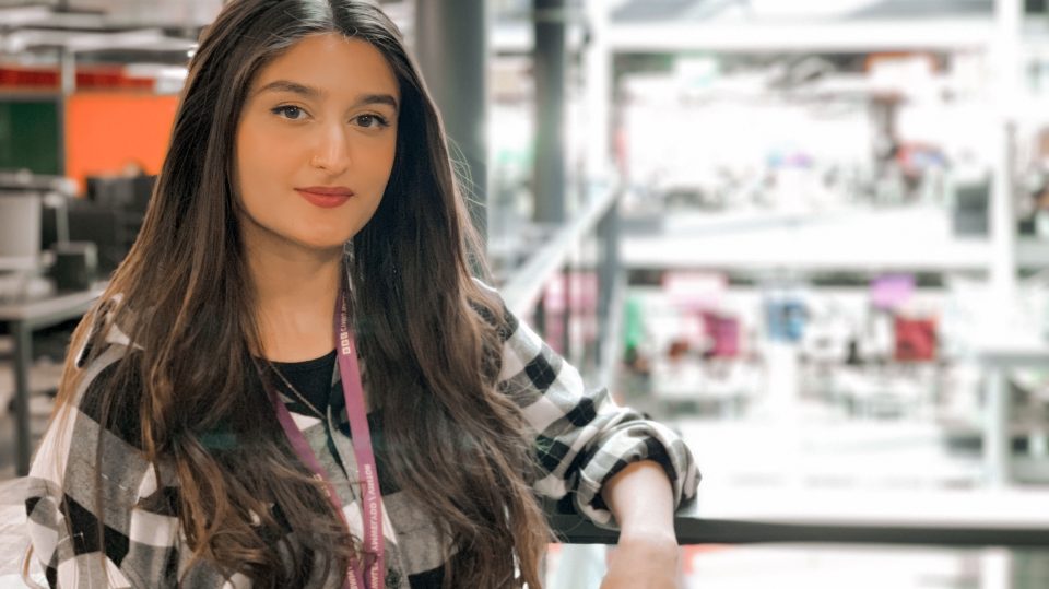 Mahjabeen looking at the camera and smiling whilst standing in the BBC offices.