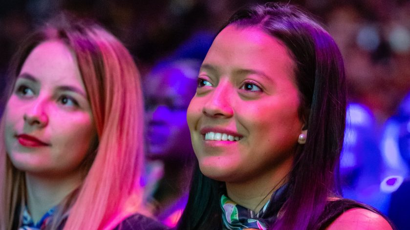Maria smiles in the audience of a formal event.