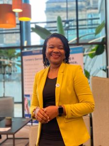 A woman wearing a yellow blazer, smiling at the camera