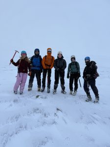 people standing on a mountain smiling. They're standing on snow.