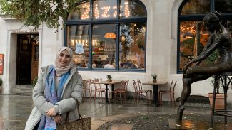 A woman leaning against a brick wall outside