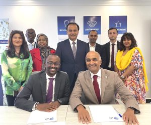 A group of people sat at a table smiling with documents in front of them