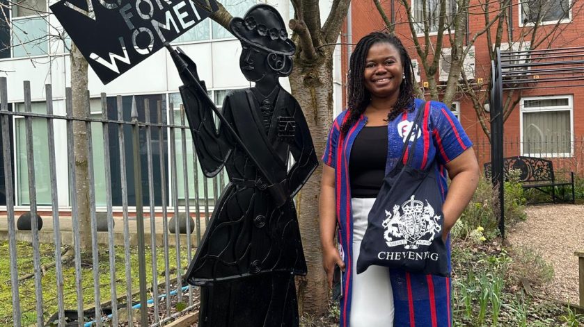 A woman standing next to a sign that says votes for women