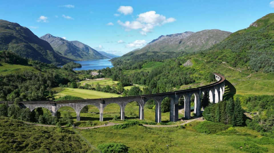 A railway bridge going across the hills in Scotland. It's sunny and a clear blue sky.