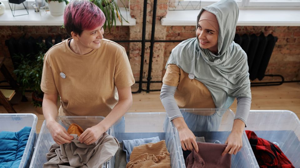 Two women talking to each other as they fold clothes