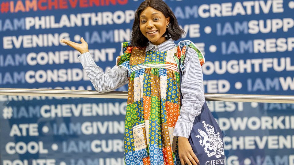 A woman standing and smiling in front a sign with IAMCHEVENING on it